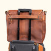 Robust tan leather travel bag mounted on a suitcase handle, featuring multiple compartments and a durable design for frequent travelers.