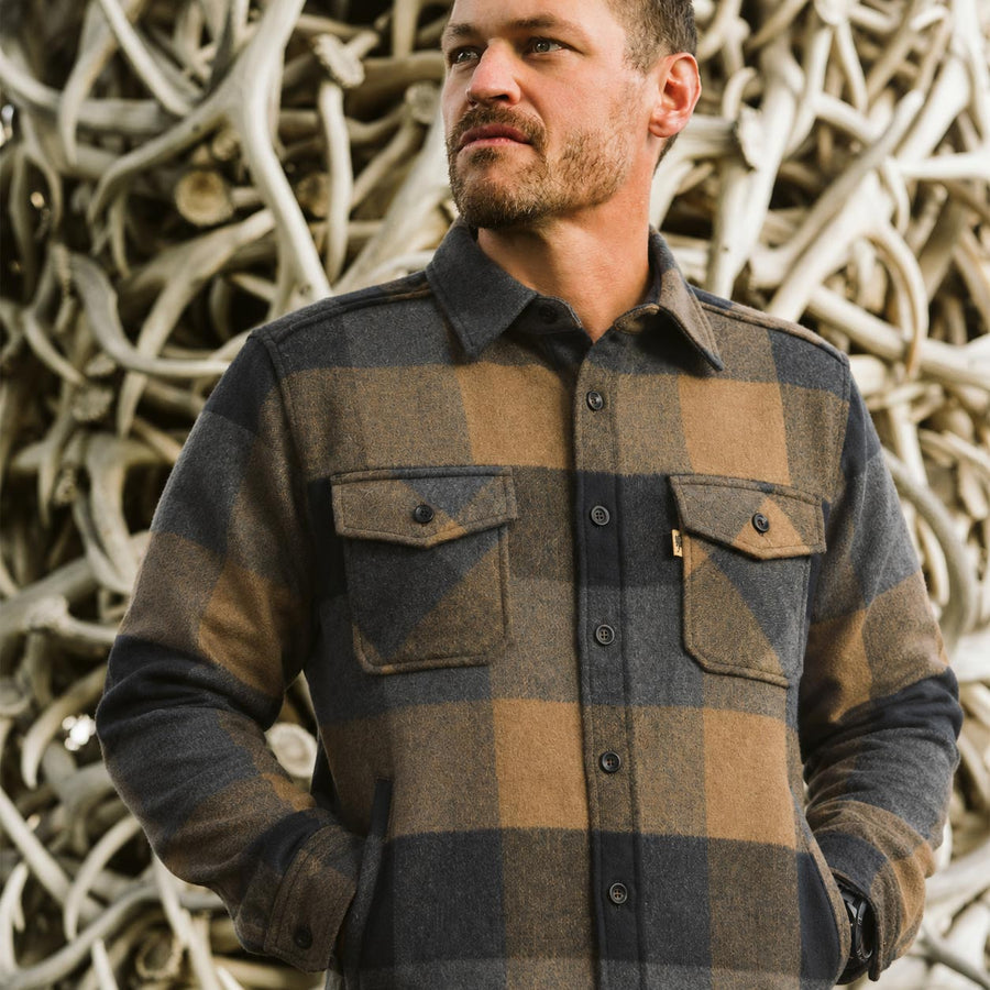 Man wearing a plaid shirt standing in front of Jackson Hole shed sculpture