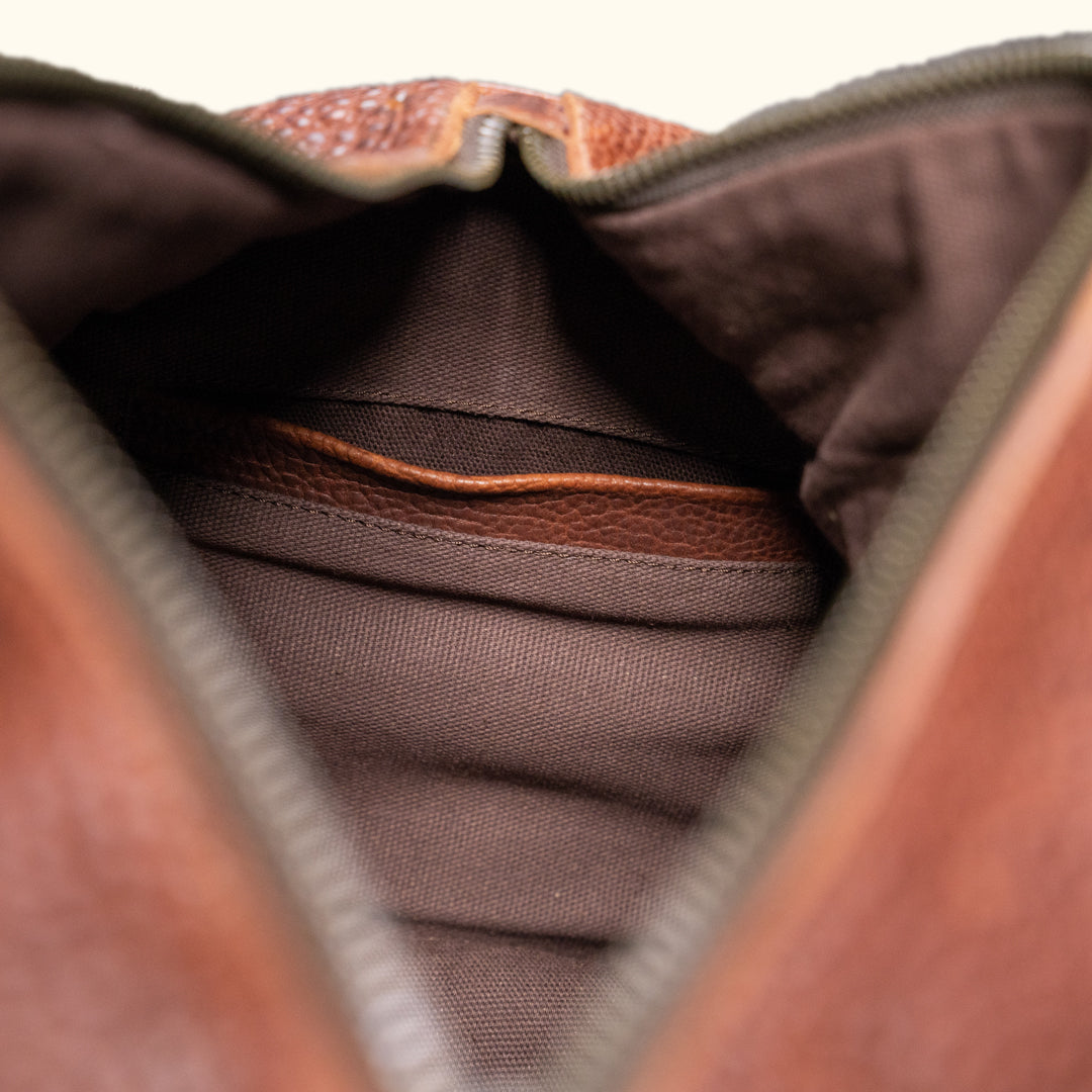 Close-up of a brown leather duffle bag interior, showcasing a simple, spacious compartment.