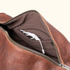 Brown leather duffle bag interior, featuring a single, large storage compartment.