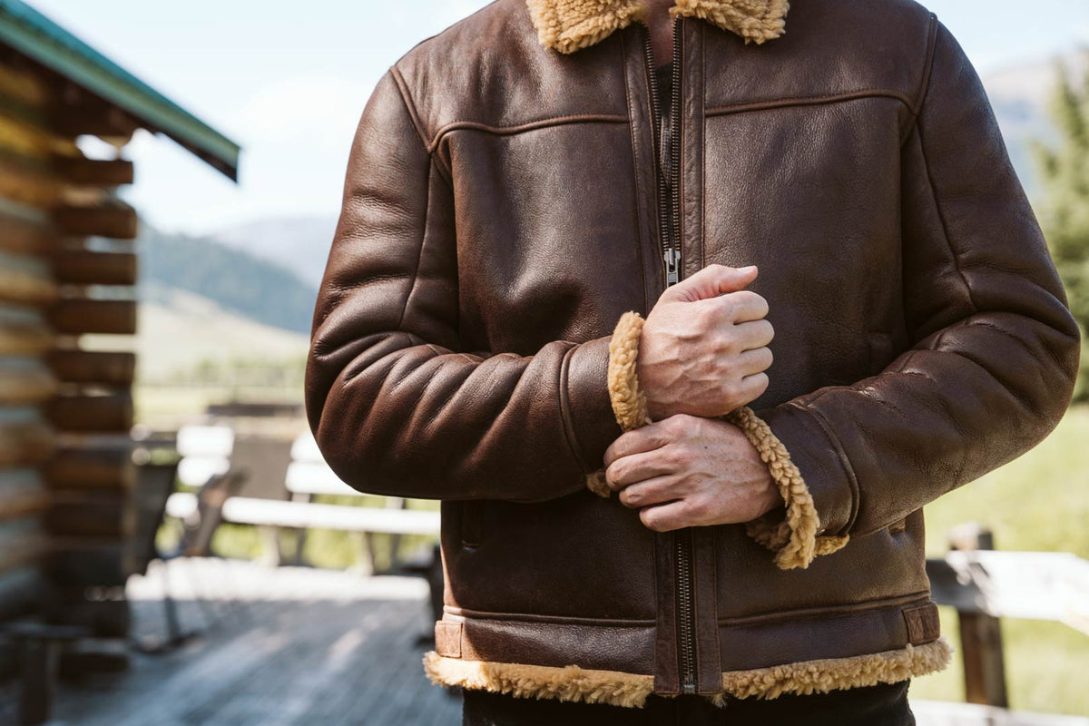 Brown shearling leather bomber jacket worn outdoors in the mountains