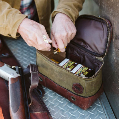 Detailed shot of a man preparing shotgun shells in a leather and canvas hunting bag.