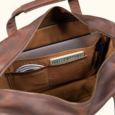 Organized interior of a brown leather briefcase, perfect for carrying a laptop and daily essentials.