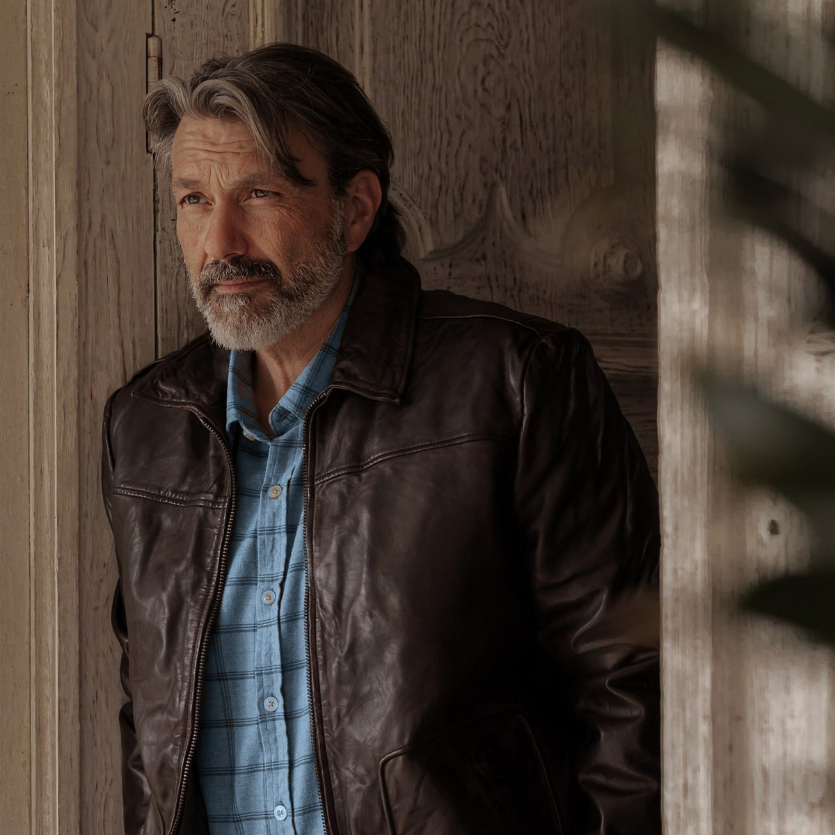 Man leaning in a doorway in the Windsor Cotton Shirt in Sky Pane and a brown leather jacket