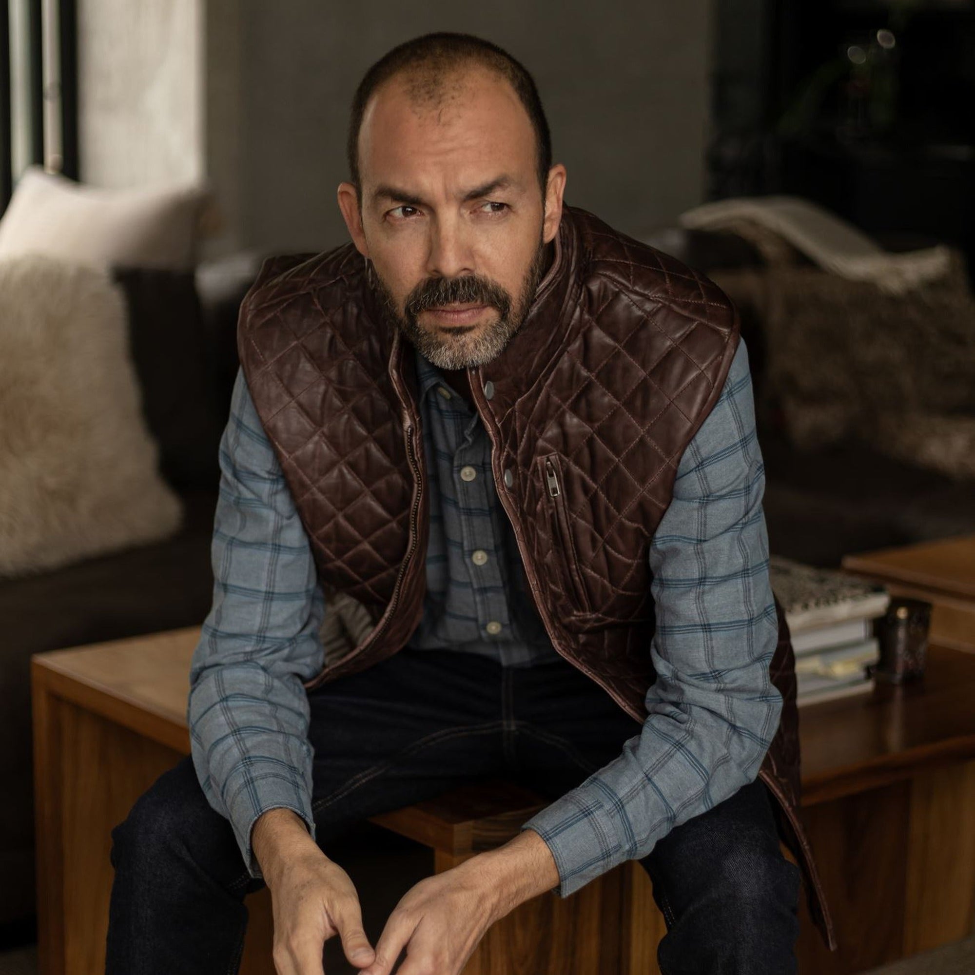 Seated man in the Windsor Cotton Shirt in Sky Pane under a quilted leather vest