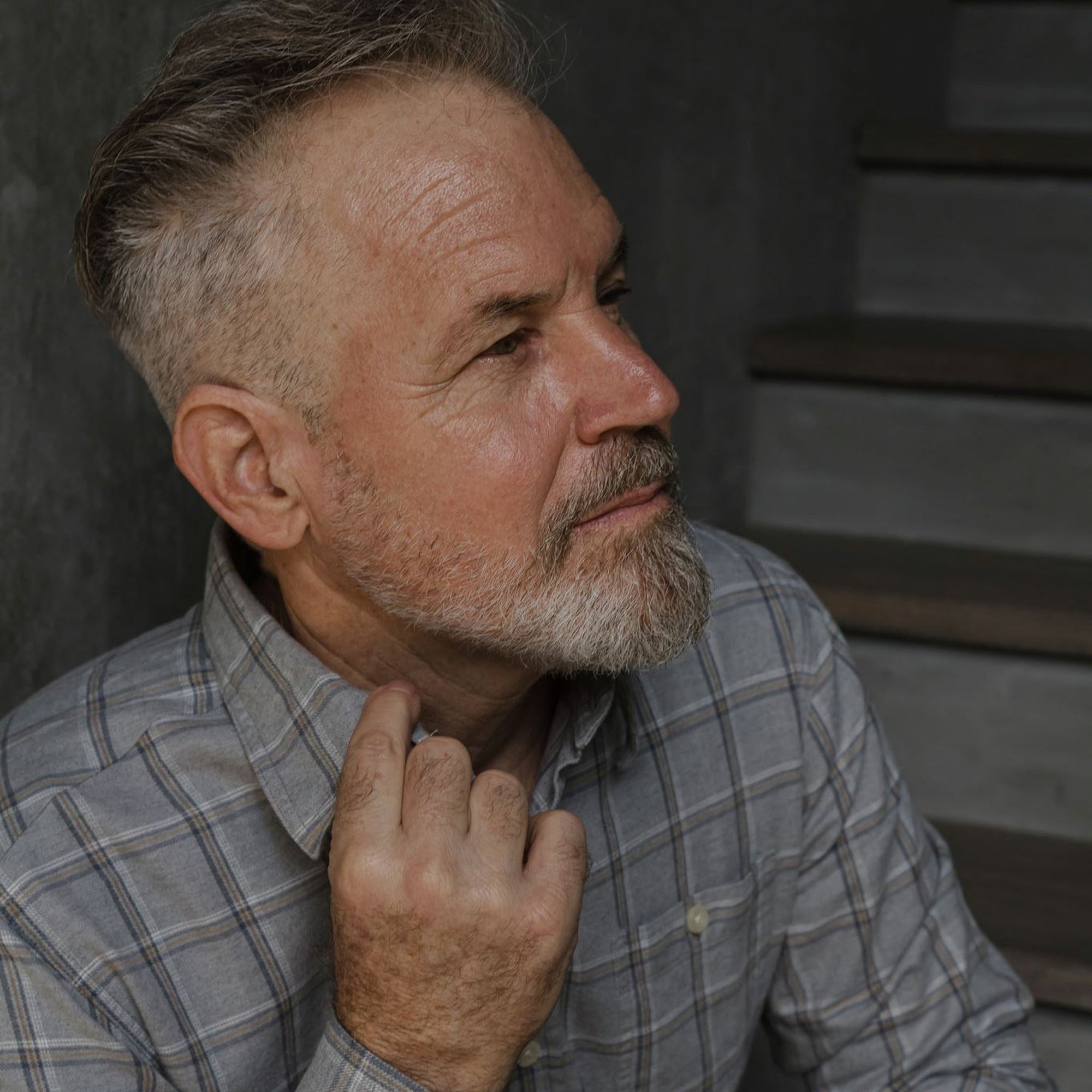 Man in the Windsor Cotton Shirt in Stone Pane, in profile with a hand at the collar