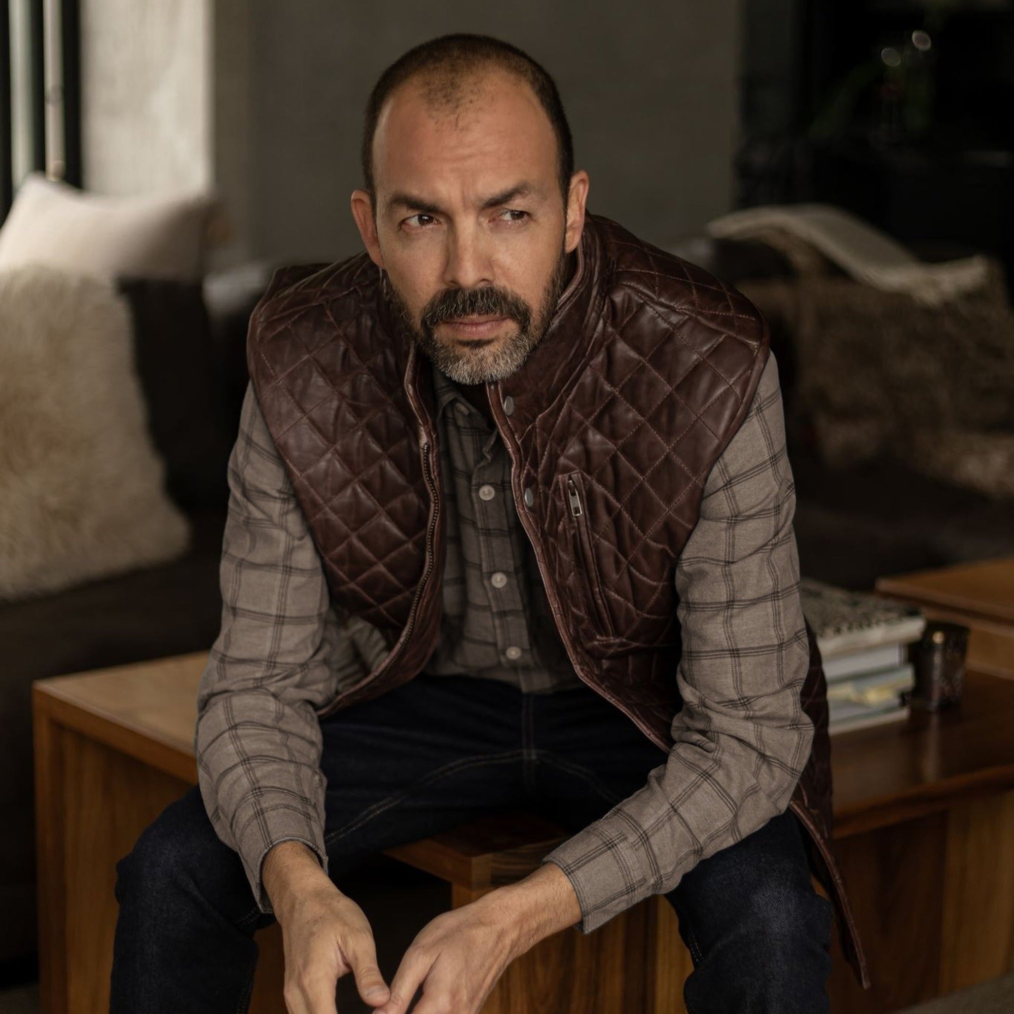 Seated man in the Windsor Cotton Shirt in Timber Pane under a quilted leather vest