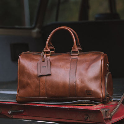 High-quality leather duffle with robust carry handles, adjustable shoulder strap, and large zippered opening.