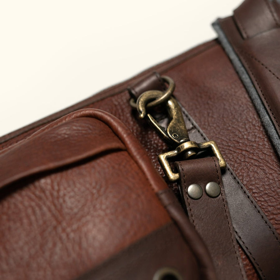 Close detail of antique brass buckle and leather strap hardware on a full grain leather shotgun case
