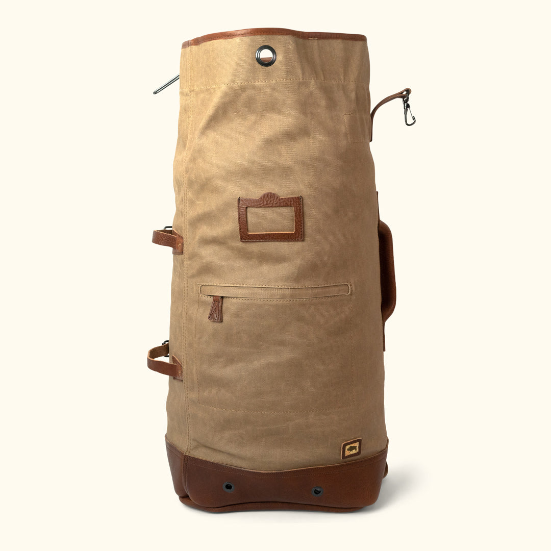 https://buffalojackson.com/cdn/shop/products/Dakota_Waxed_Canvas_Military_Sea_Bag_Backpack_Field_Khaki_With_Chestnut_Brown_Leather_-_6-of-6.jpg?v=1685114240
