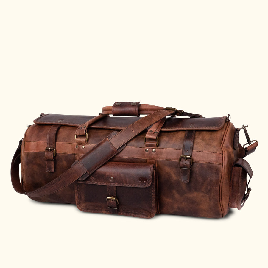 Dark oak buffalo leather duffle bag with adjustable shoulder strap, top handles, and secure buckle closures for travel.