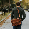 Man outdoors interacting with a high-quality Roosevelt leather briefcase in amber brown, highlighting its practical design