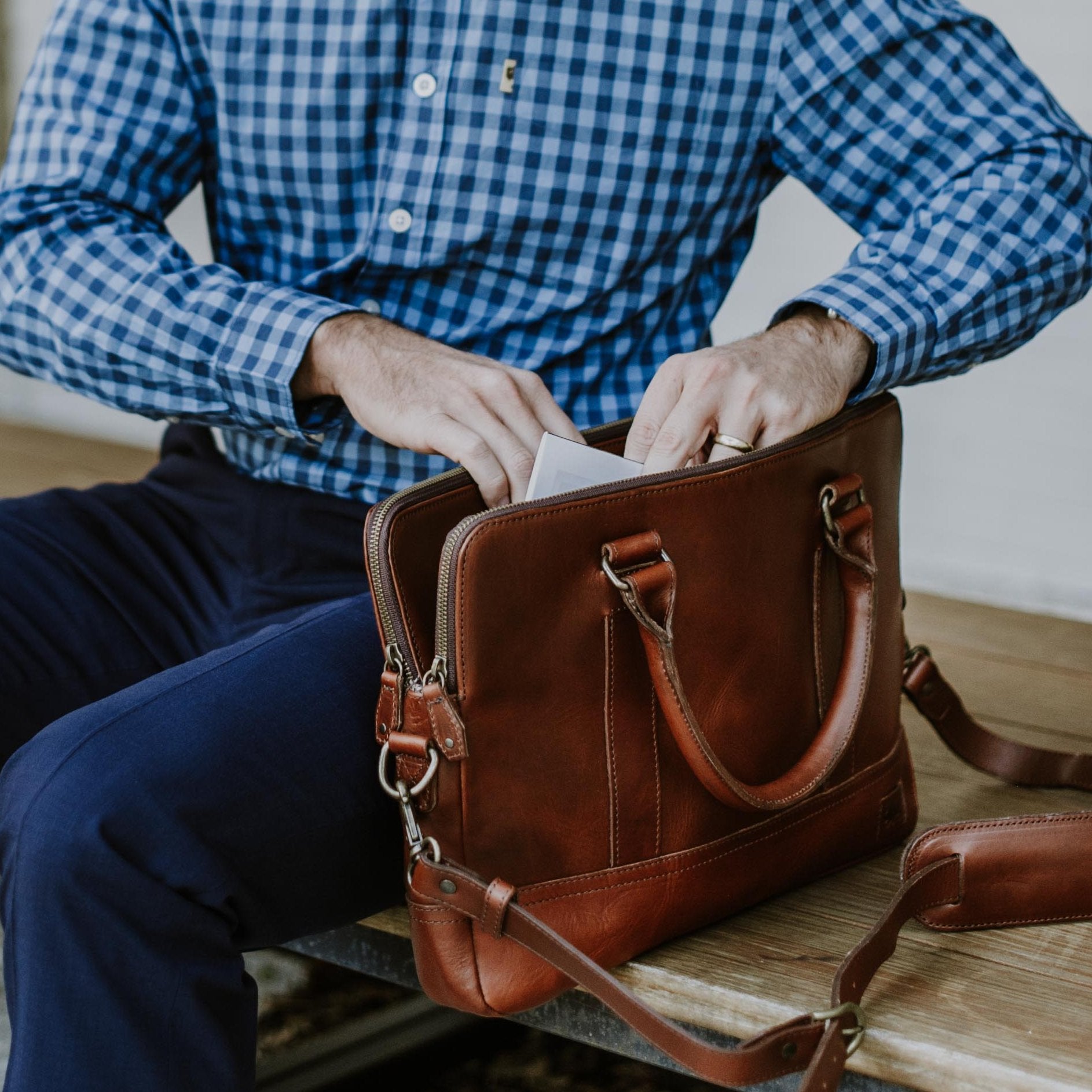 Man opening the Jefferson Leather Attaché in Elderwood brown to reach his laptop