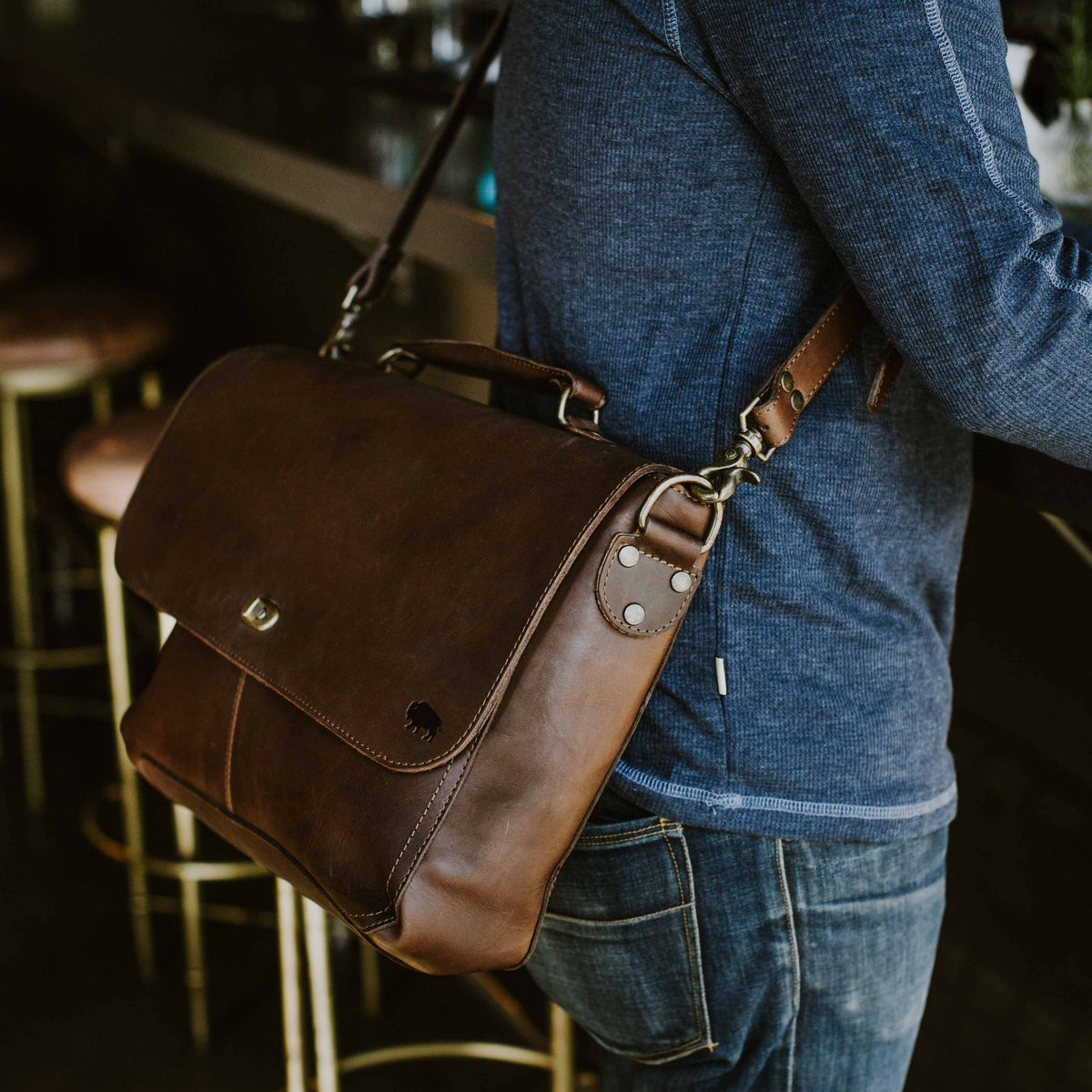 Man wearing Roosevelt Full-Grain Leather Messenger Bag in Dark Oak — rear zipper pocket detail, casual lifestyle shot