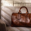 Chic tan leather duffle, perfect for jet-setters, with a minimalist design and functional elegance.