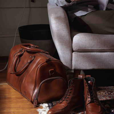 Designer leather travel duffle in warm tan, perfect for weekends, with comfortable straps and sleek design.